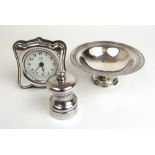 An Elizabeth II silver pedestal bowl together with a silver pepper mill and a silver fronted clock.