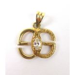 A yellow metal pendant in the form of a pair of entwined 'Gs',