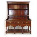 An early 20th century oak dresser in the 18th century style, the plate rack above three drawers,