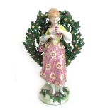 A 19th century Staffordshire style porcelain figure of a lady with grapes standing before a brocage,