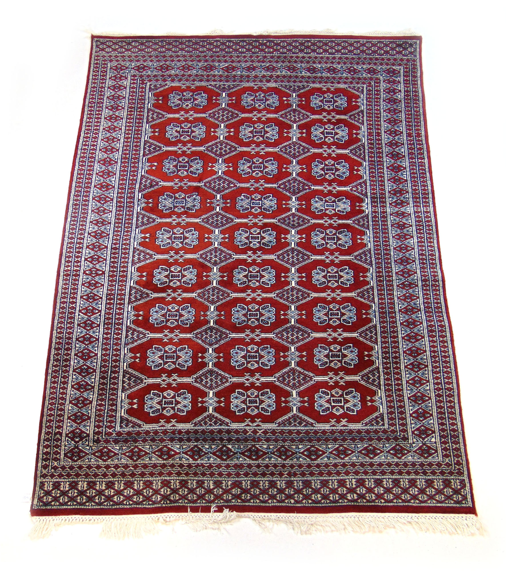 A handwoven Indian rug, the multi line border enclosing a red ground field with octagons,