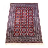 A handwoven Indian rug, the multi line border enclosing a red ground field with octagons,