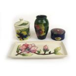 Four pieces of Moorcroft pottery comprising of a preserve pot, small vase, trinket pot and tray.