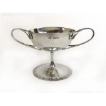 An Arts & Crafts silver twin handled pedestal cup in the manner of Charles Robert Ashbee.