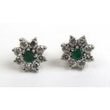 A pair of white metal, emerald and diamond cluster earrings. Total diamond weight approximately 0.