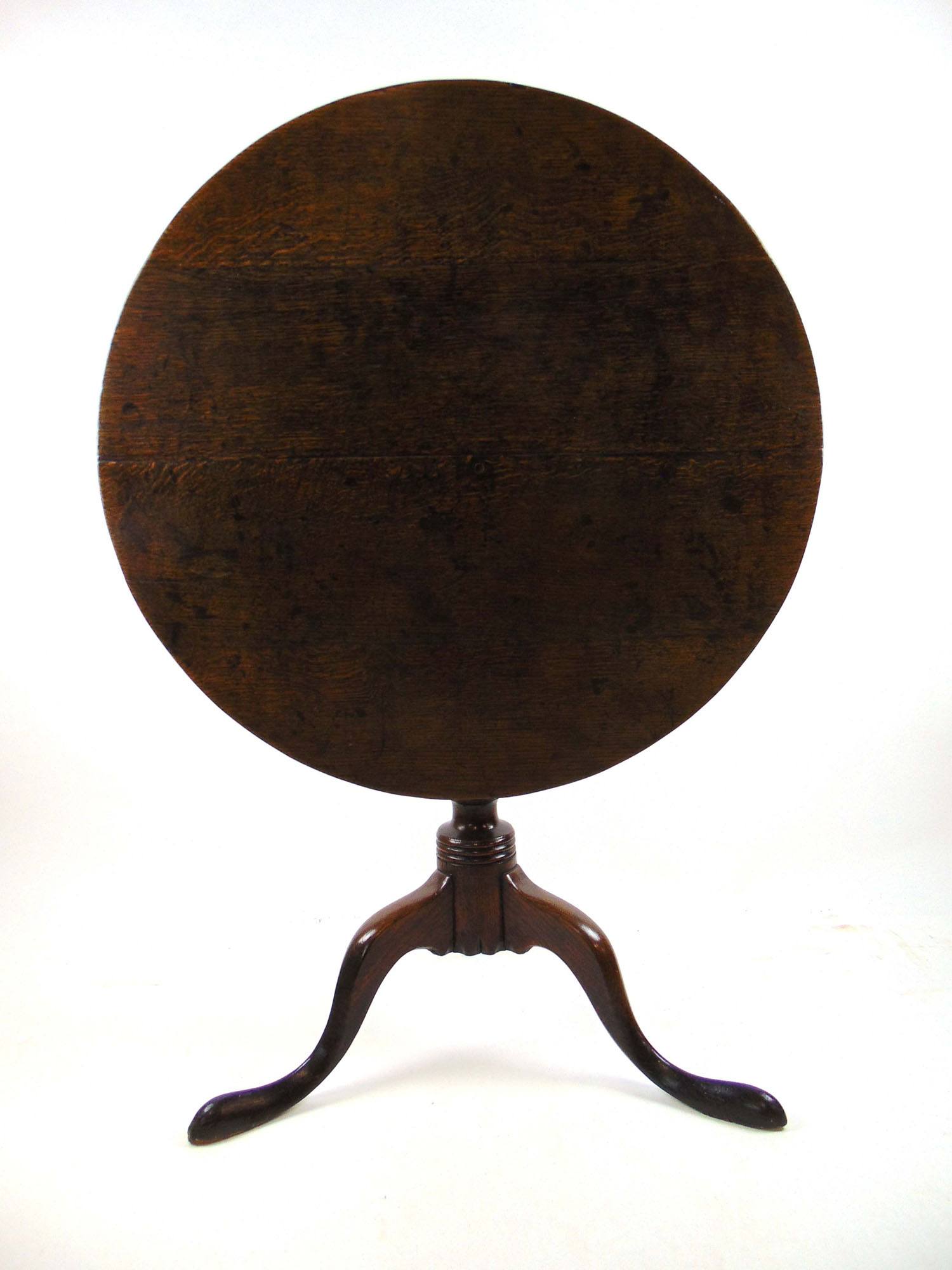 An 18th century oak tilt top tripod table, the circular top over turned column and three swept legs,