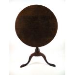 An 18th century oak tilt top tripod table, the circular top over turned column and three swept legs,