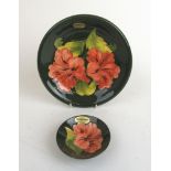 A Moorcroft plate decorated in the 'Hibiscus' pattern on a green ground,