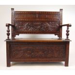 A late Victorian carved oak box settle,