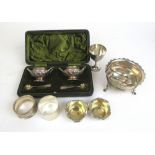 An assortment of silver items to include a cased cruet set, egg cup, napkin rings, sugar bowl etc.