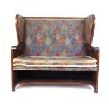 A late 19th century walnut settle with floral carved sides upholstered in a patterned fabric, h.