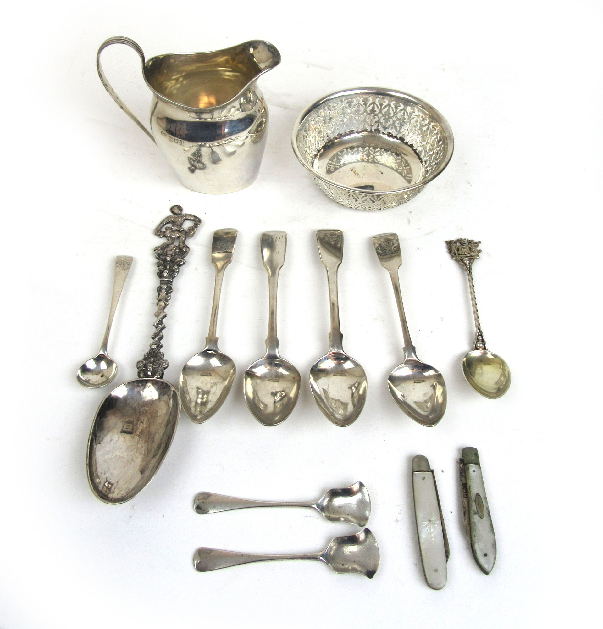 An assortment of silver and white metal items to include cream jug, pierced bowl, spoons,