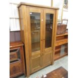 A modern oak cabinet having a pair of glazed doors to top with panelled doors below