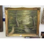 A gilt framed oil on canvas of a stream running through wooded scene