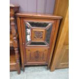 An Edwardian walnut cabinet having a bevel glass mirrored door