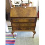 A mid-20th century walnut veneered fall front bureau having one leg missing