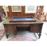 A reproduction oak twin pedestal desk having a carving to doors and drawer