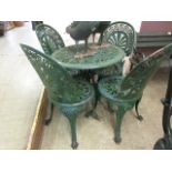 A green painted circular aluminium garden table with a set of four similar chairs