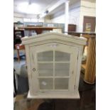 A cream painted wall mounted glazed cabinet