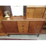 A mid-20th century dresser base having three drawers flanked by cupboard doors