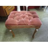 A mid-20th century walnut framed stool upholstered in a pink button fabric