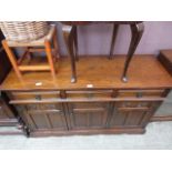 A reproduction oak dresser base having three drawers above cupboard doors