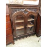 A modern ebony bookcase having two glazed doors flanked by turned columns