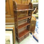 A modern open bookcase with pierced sides over four drawers