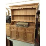 A pine dresser with a plate rack, open shelving,