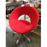 A red upholstered swivel chair on a chrome base