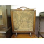 An early twentieth century oak fire screen with a needle work panel of a dancing couple