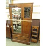 An arts and crafts oak wardrobe with beveled mirror door flanking leaded glass over single drawer