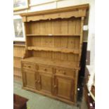 A pine dresser with a plate rack, open shelving,