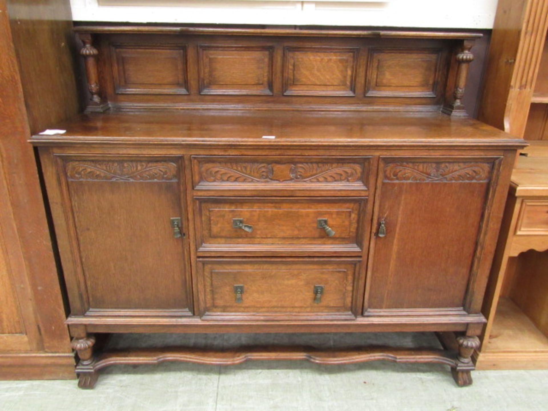 An early 20th century oak sideboard having three drawers flanked by cupboard doors