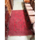 A hand woven Afghan rug with a multi line border enclosing a red ground field with eight octagons,