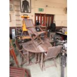 A distressed teak folding garden table with a set of four matching chairs