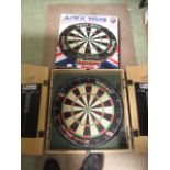 A boxed dart board together with another dart board in case