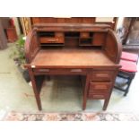 An early 20th century oak roll top desk