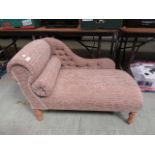 A modern small scale chaise lounge upholstered in a cut button back fabric