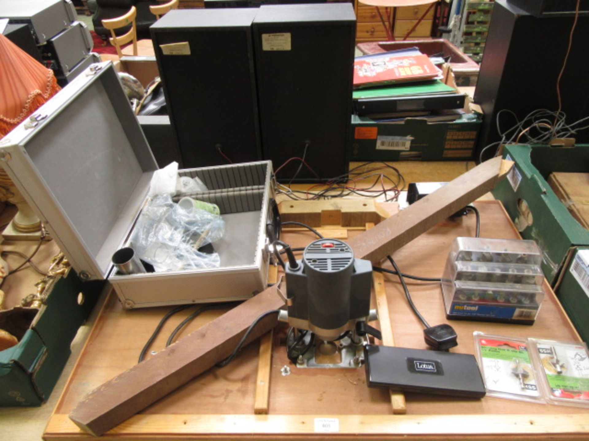 A table top mounted router with bit set and a case containing other attachments