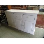 A modern white painted dresser base with three drawers over three cupboard doors