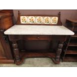 An Edwardian walnut washstand having tiled splashback over marble top on turned legs