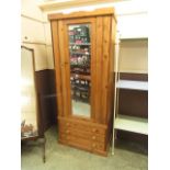 A waxed pine wardrobe having a mirrored centre door with three drawers below