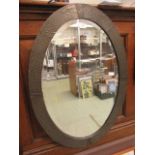 An early 20th century hammered pewter framed oval bevel glass mirror