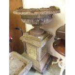 A composite stone garden urn on plinth