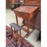 An early 20th century oak school desk with fold out seat and lift up slope