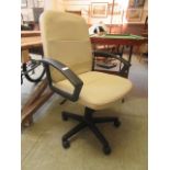 A cream upholstered black framed swivel office chair