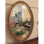 An ornate gilt framed oval bevel glass wall mirror