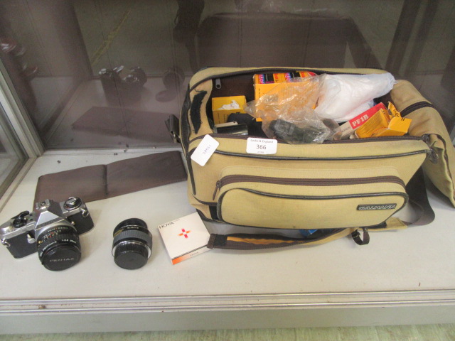 A camera case containing an assortment of camera equipment together with a Pentax camera and lens