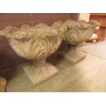 A pair of composite stone garden urns with leaf design bowls